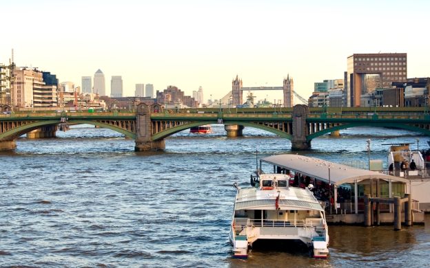 Captivating view of cruise ships sailing on London Eye River: London cityscape and iconic Tower Bridge in the distance create a stunning backdrop.